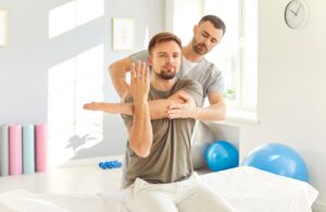 MaleProfessionalChiropractorOrPhysicalTherapistWorkingWithCaucasianMans - Saint Elizabeth Community Short Term Inpatient Rehab